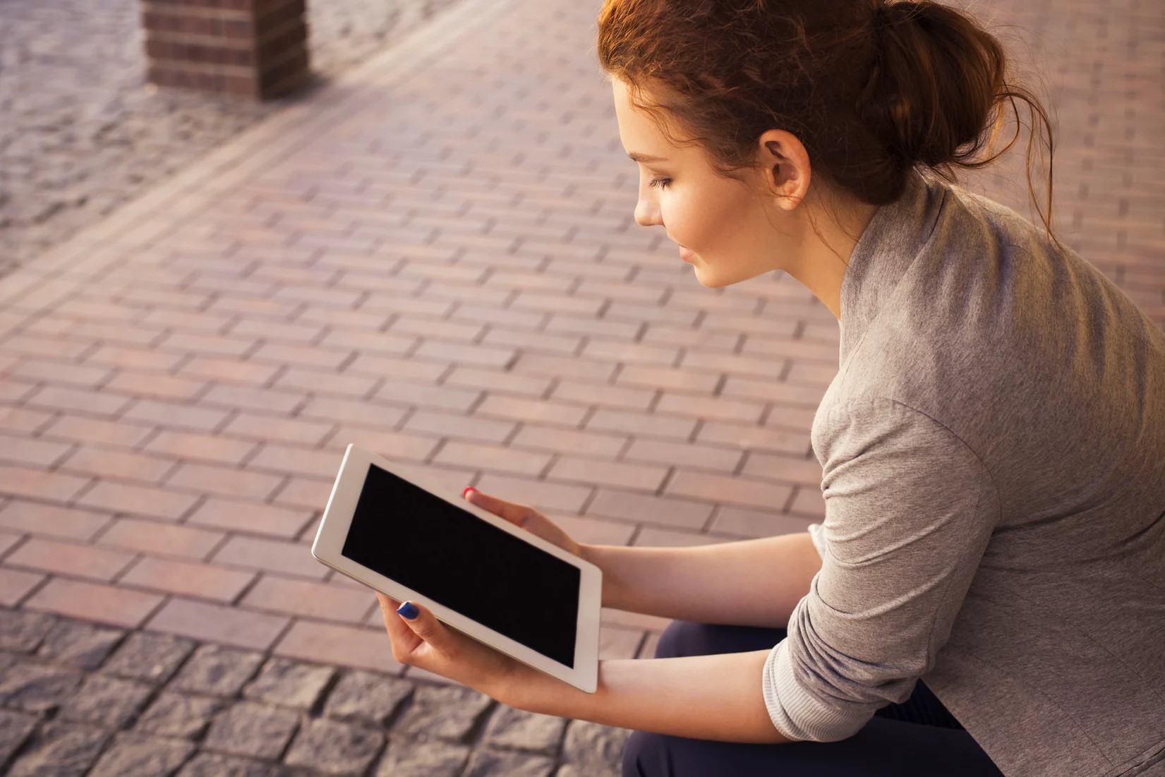 A person smiling at a turned-off tablet.