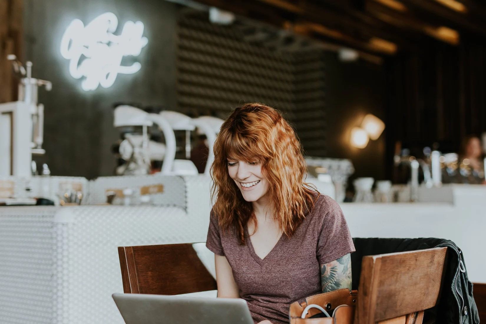 A woman smiling at a laptop.