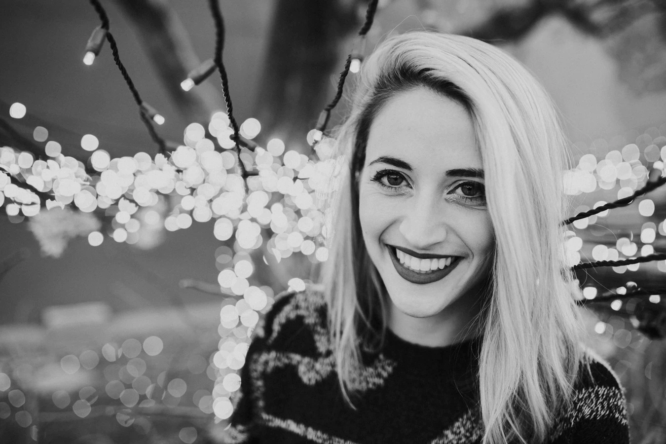 A woman smiling in a black-and-white photo.