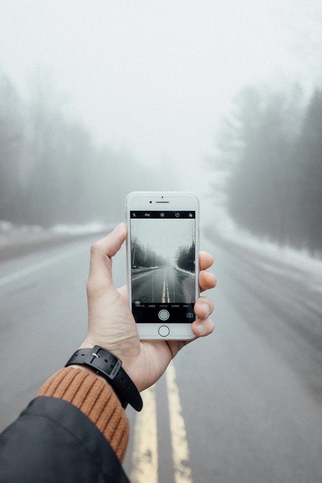 A person taking a picture of a road in the winter.