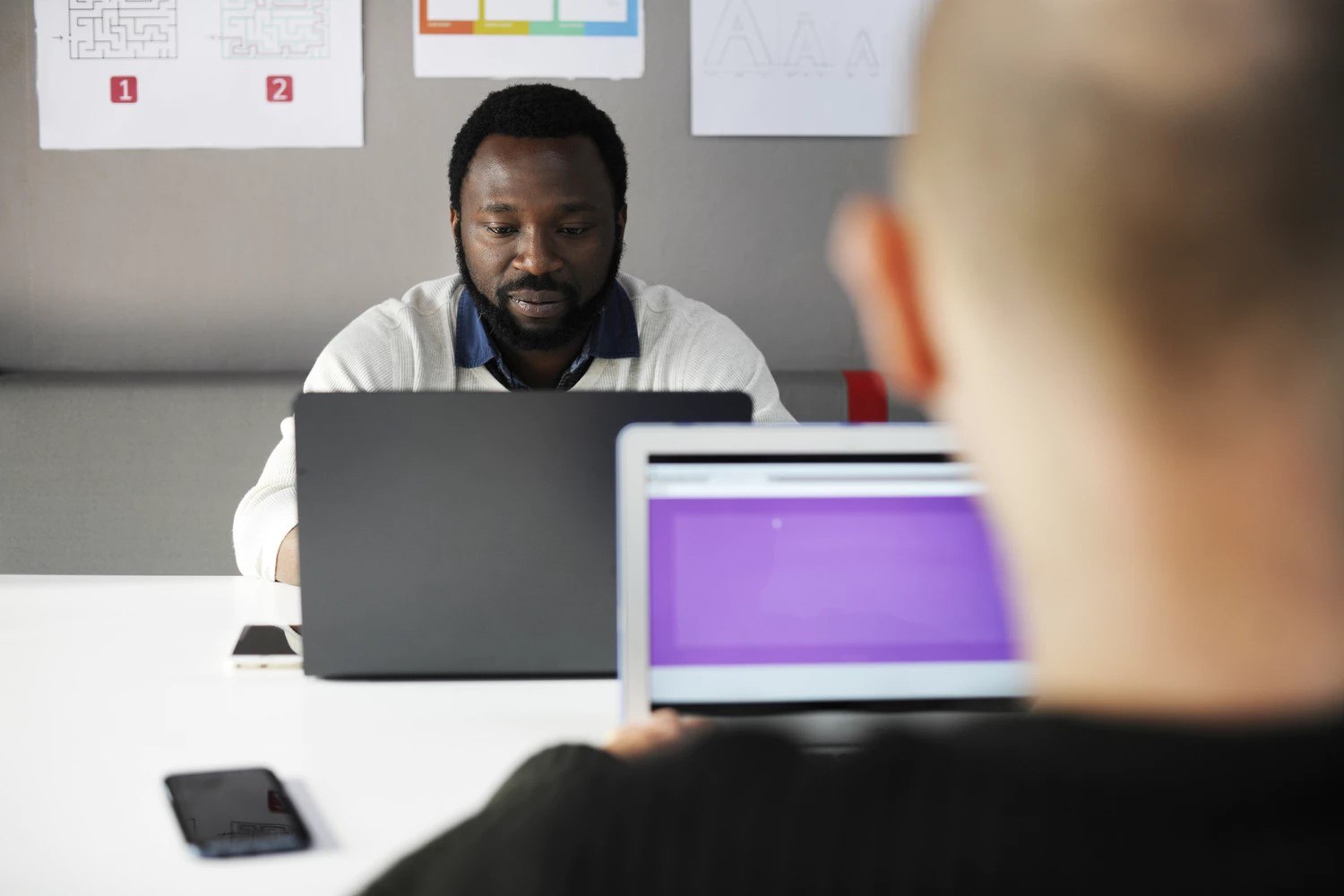 Two people working on laptops next to each other.