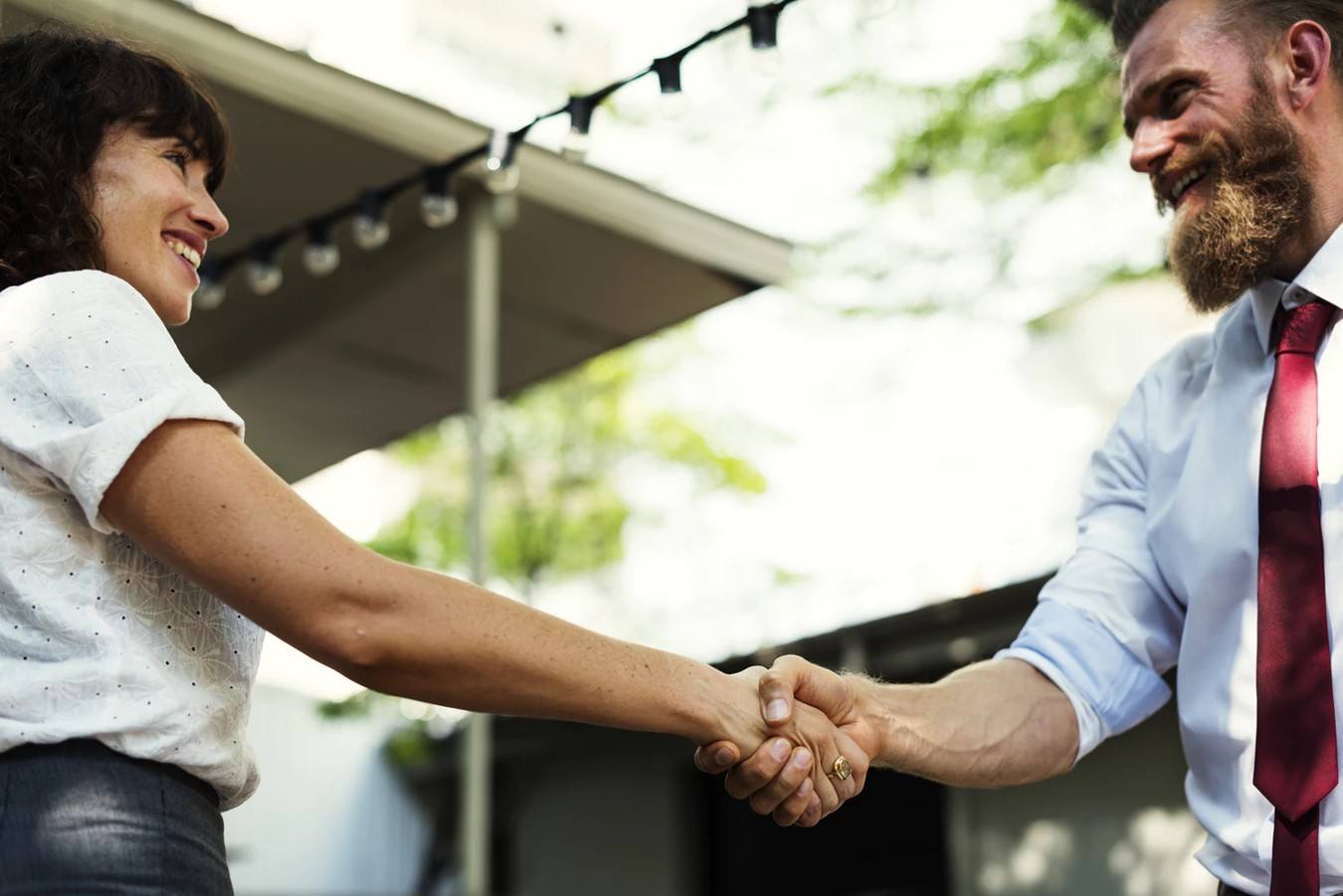 A man and a woman shaking hands and smiling.